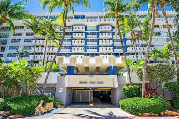 Front view of a multi-story residential building with balconies and a covered entrance.
