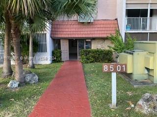 Front view of a building entrance with a red pathway leading to it.