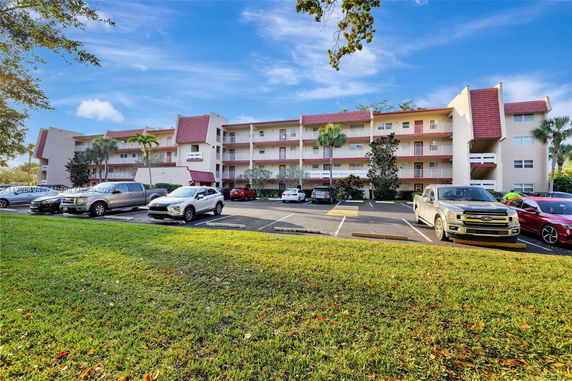 Front view of a multi-story residential building with a parking area in front.