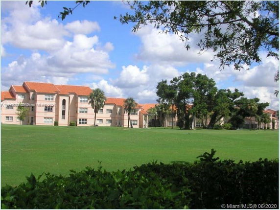 View of residential buildings with red roofs and cloudy sky.