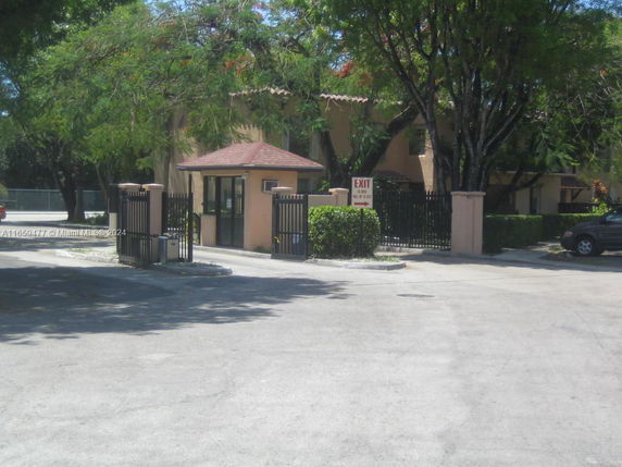 Front view of a gated entrance with a small guardhouse.