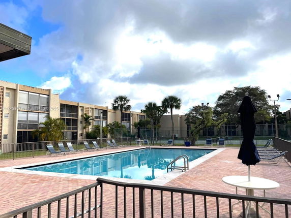 Outdoor swimming pool area with lounge chairs and surrounding buildings.