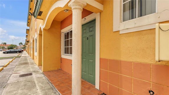 Front view of a townhouse with a green door and decorative pillars.