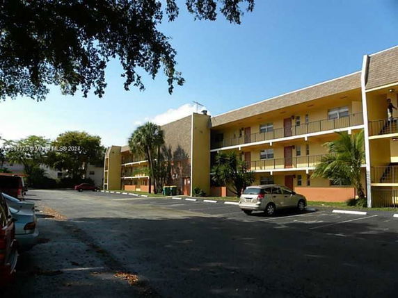 Front view of a multi-story apartment building with balconies and exterior stairs.