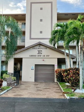 Front view of a multi-story building with a garage entrance and balconies.