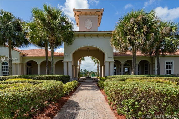 Front view of a building with arched entrance and palm trees.