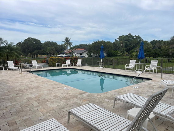 Outdoor swimming pool with lounge chairs and umbrellas.
