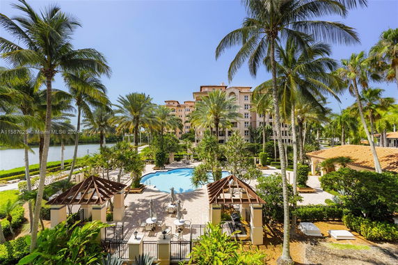 View of a swimming pool area with a backdrop of palm trees and a large residential building.