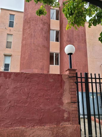 Front view of a multi-story building with circular elements and a red textured facade.