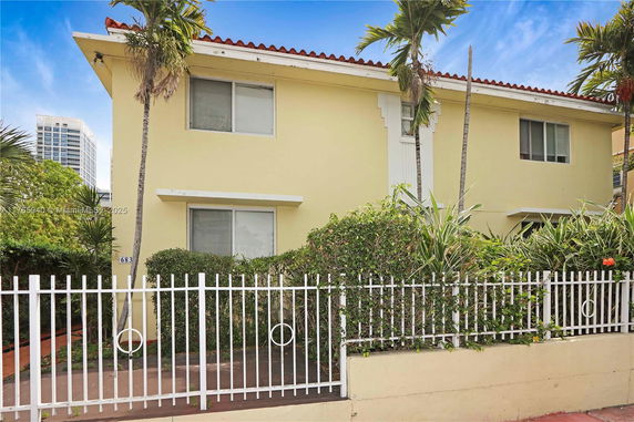 Front view of a two-story house with a white fence.