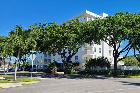 Front view of a multi-story white building with balconies.