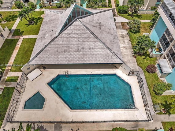 Aerial view of a swimming pool adjacent to a building with a geometric roof design.