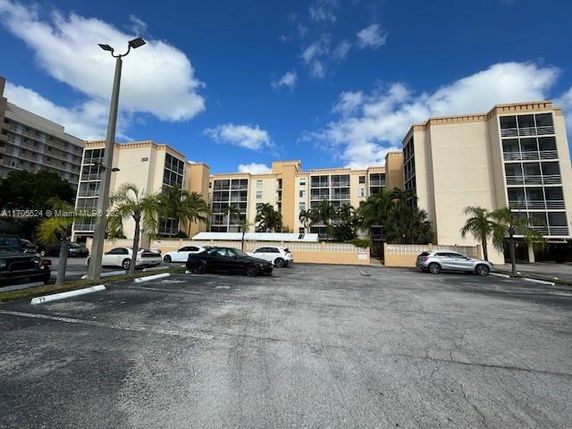 Front view of a multi-story residential building with parking in front.