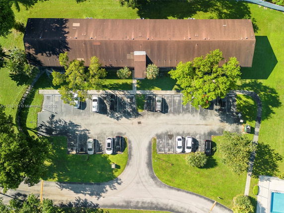 Aerial view of a building with adjacent parking area and parked cars.