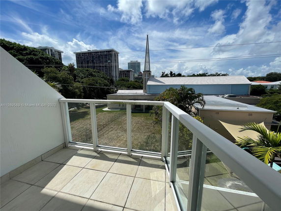 View of the surrounding area from a balcony showing buildings and trees.