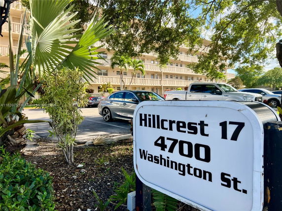 Outdoor parking area in front of a multi-story building with several cars parked.