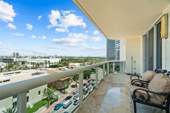 Balcony with chairs overlooking a cityscape with roads and buildings.