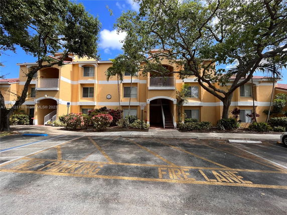 Front view of a multi-story apartment building with a central staircase and yellow exterior.