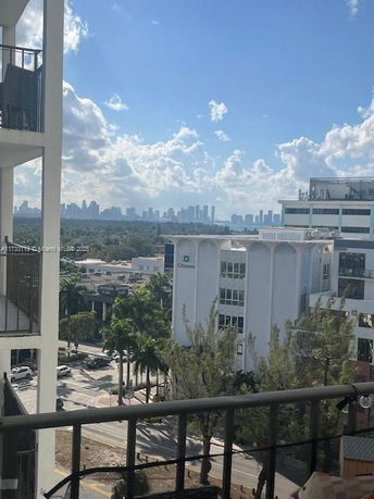 Panoramic view of a cityscape with buildings and a distant skyline seen from a balcony.