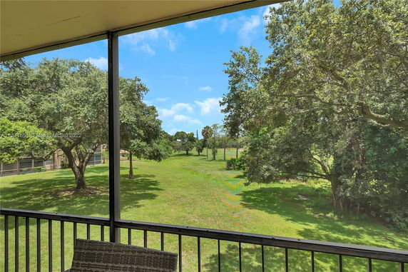 View from a balcony overlooking a grassy area and trees.
