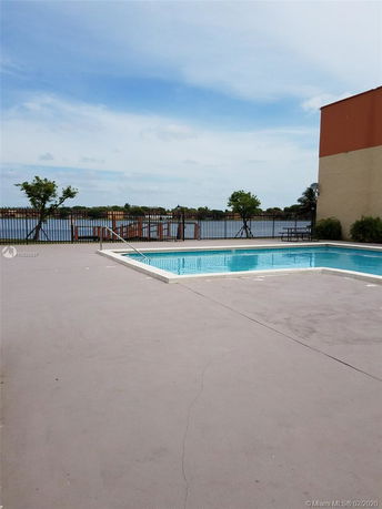 Outdoor swimming pool with a view of a lake and surrounding fencing.