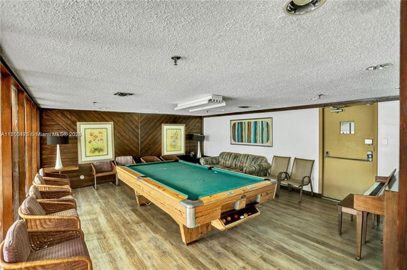 Room with a pool table, seating area, and wall art.