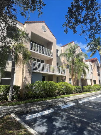 Front view of a multi-story residential building with balconies and reserved parking spaces.