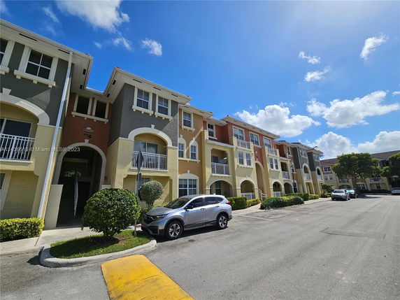 Front view of a multi-story residential building with balconies and arched windows.