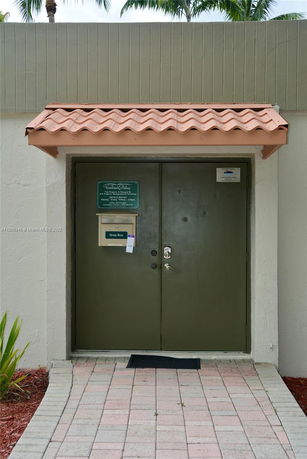 Front view of an entrance with a heavy double door and a small canopy.