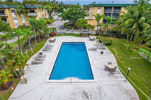 Outdoor swimming pool area with lounge chairs and tables.