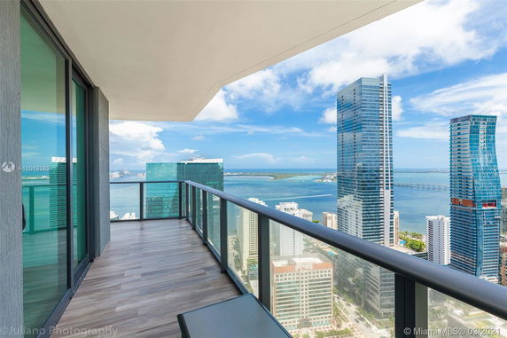 Balcony view of high-rise buildings and ocean in the background.
