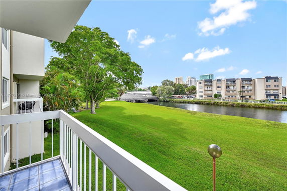View from a balcony overlooking a grassy area and a waterway with buildings in the distance.