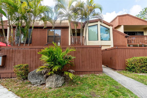Front view of a multi-story townhouse with wooden fencing and a small balcony.