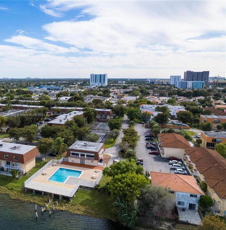 Aerial view of a residential area with multiple buildings, a swimming pool, and surrounding greenery.