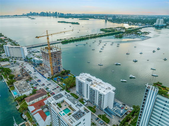 Aerial view of waterfront buildings and construction site near a water body with boats.