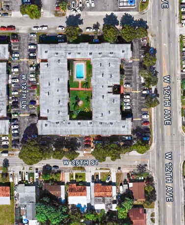Aerial view of a building complex with a central swimming pool and surrounding parking areas.