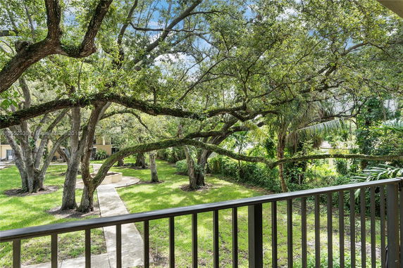 View from a balcony overlooking a well-maintained garden area with trees and a pathway.