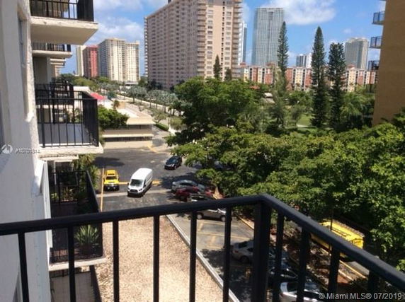 View from a building balcony overlooking a parking area and multiple high-rise buildings.