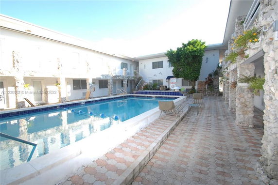 Outdoor swimming pool area surrounded by a building with stone cladding.