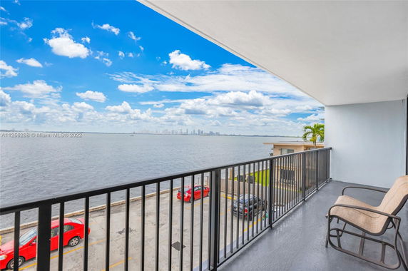 Balcony view overlooking a body of water with a city skyline in the distance.