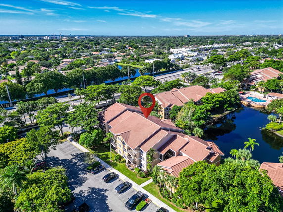 Aerial view of an apartment complex surrounded by trees and water bodies.