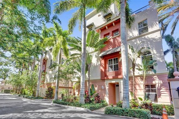 Front view of a multistory residential building with palm trees.
