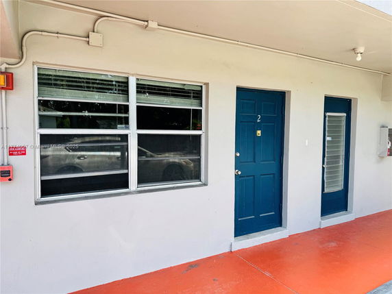 Front view of a building with two blue doors and a large window.