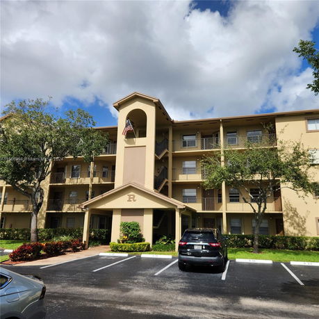 Front view of a multi-story residential building with parking area.