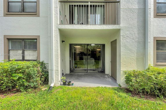 View of a building facade with sliding glass doors and a small balcony on the upper level.