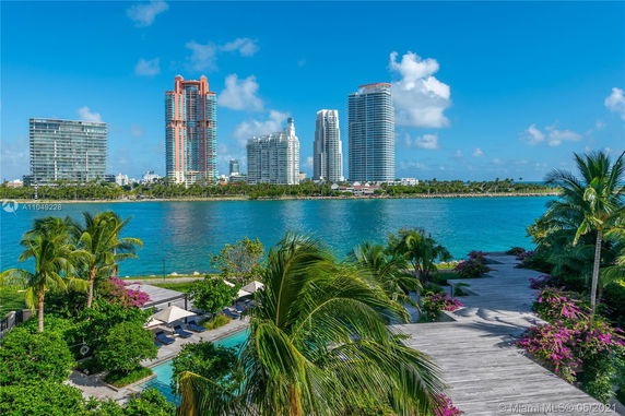 View of high-rise buildings across a body of water with a landscaped pathway and pool in the foreground.