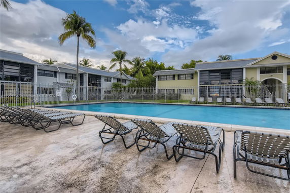 Outdoor swimming pool area with lounge chairs and surrounding buildings.