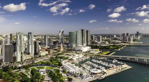 Panoramic view of a coastal city with skyscrapers and a marina.