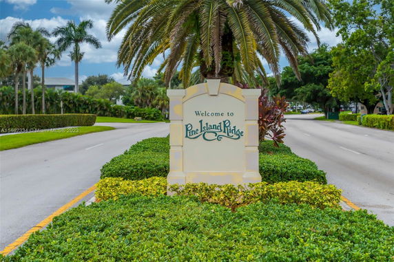 Entrance sign with palm trees in background.