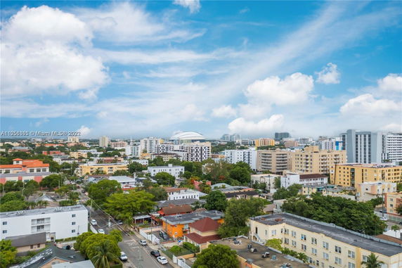 Panoramic view of a cityscape with buildings and greenery under a blue sky with clouds.